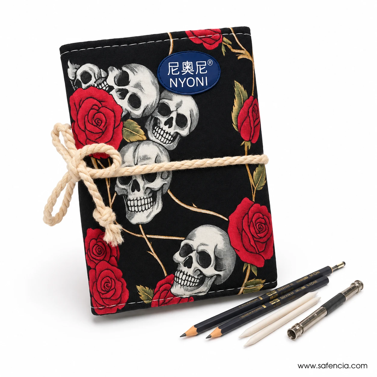 Closed Nyoni skull and red rose drawing pencil roll tied with cord beside graphite pencils and metal tools