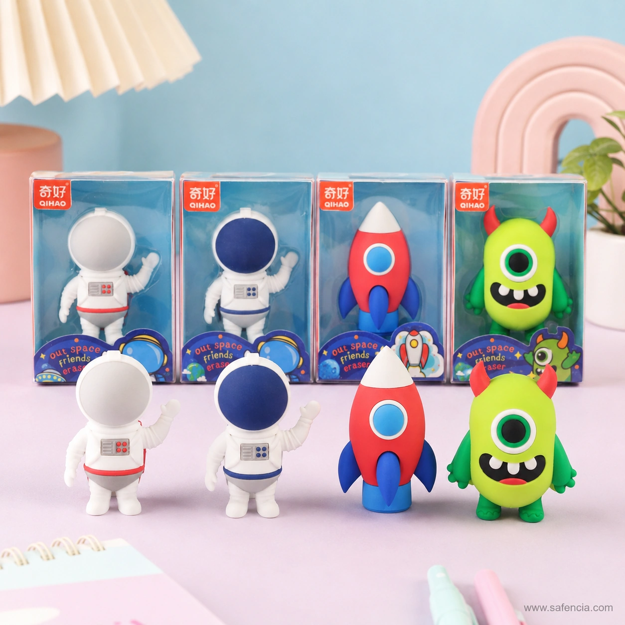 All four space eraser figures standing in a row in front of their boxes — two astronauts, red rocket and green alien
