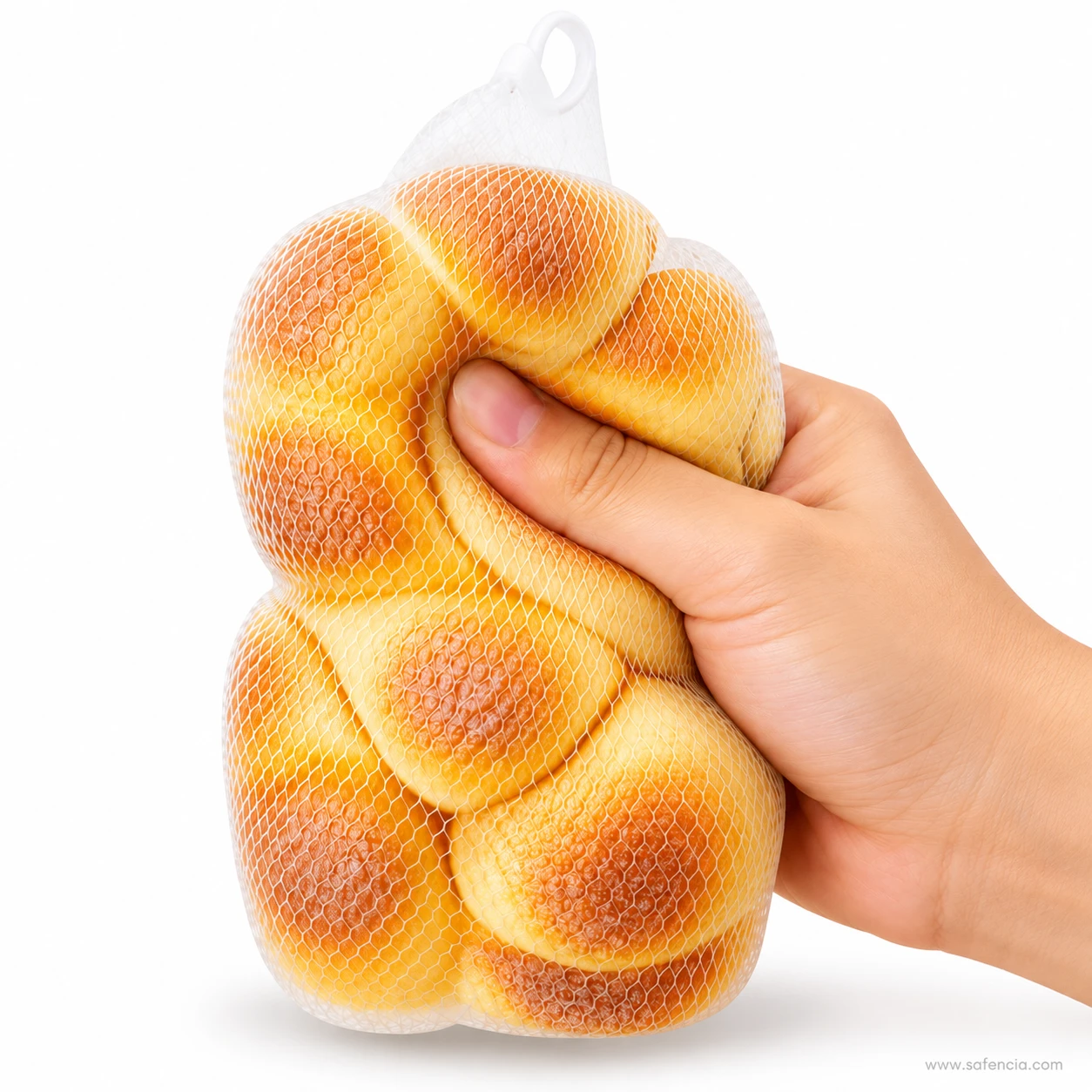 Hand squeezing the top lobes of the braided bread loaf squishy through its mesh bag