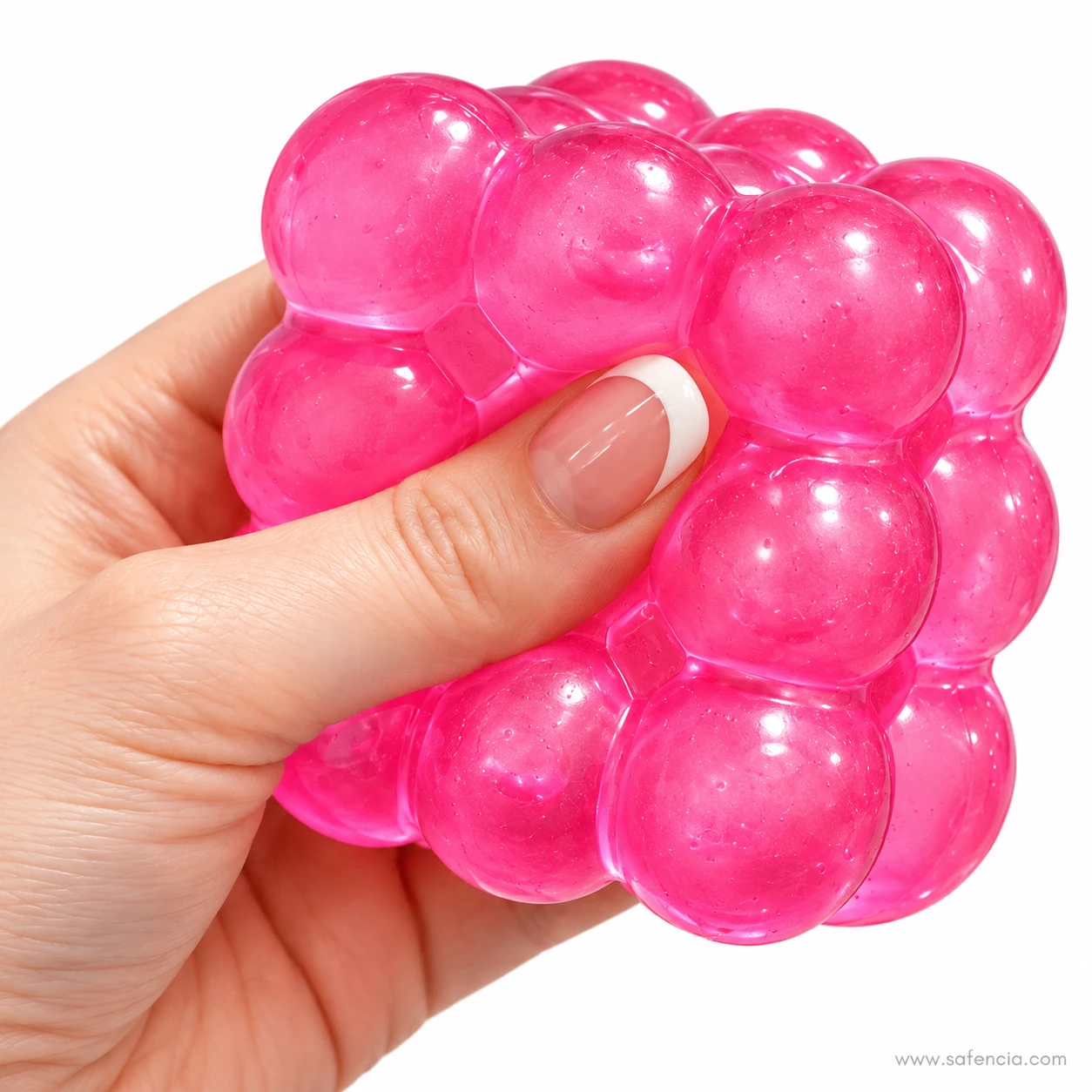 Thumb pressing into the bumpy surface of a pink bubble squishy cube held in one hand