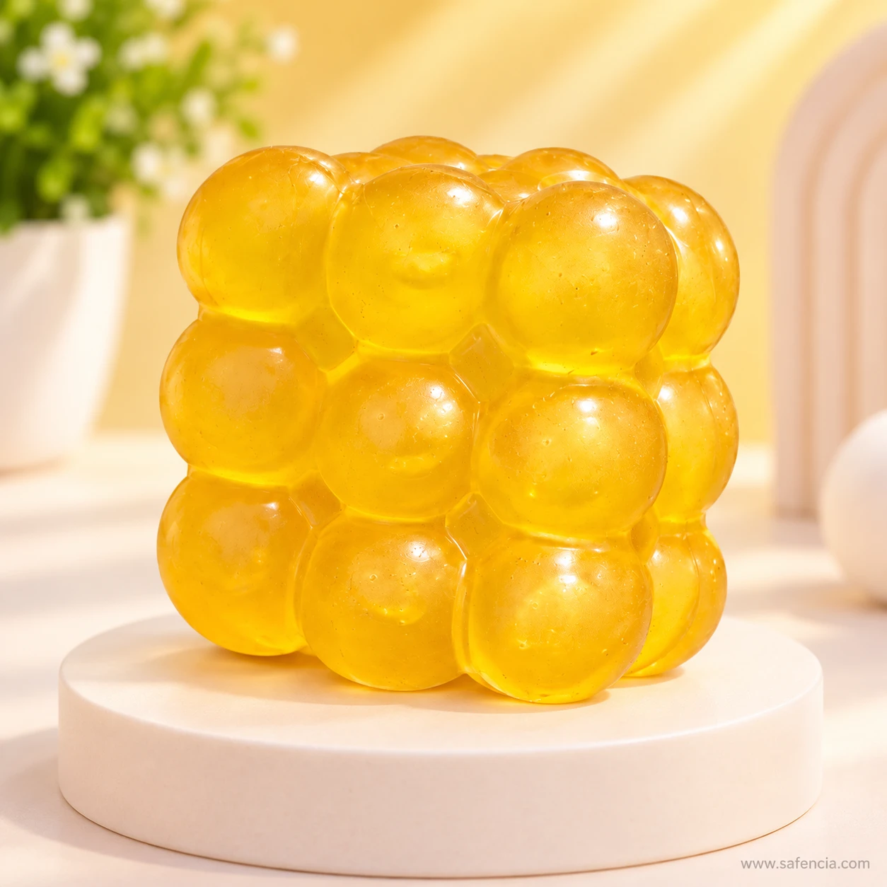 Yellow bubble squishy cube displayed on a round white stand in a softly lit room