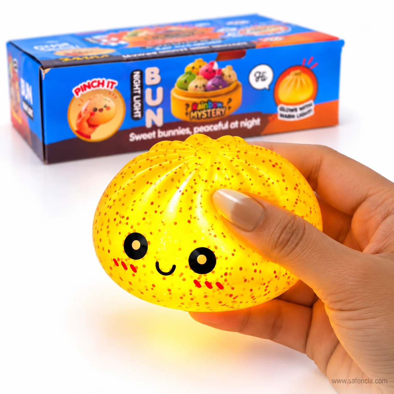 Hand pinching a glowing yellow bun squishy night light in front of its Bun Night Light box