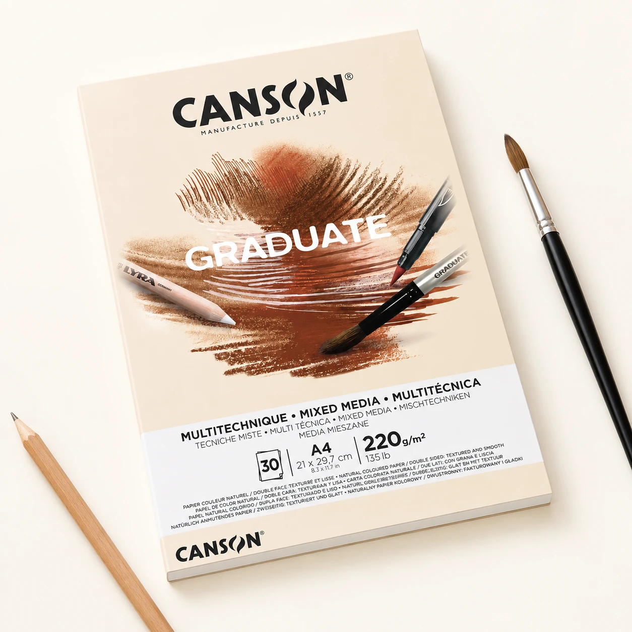 Canson Graduate yellow ochre A4 pad with paintbrush and pencil on studio table