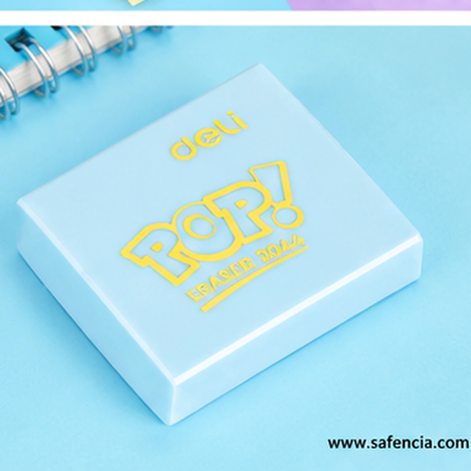 Sky blue Deli Pop eraser with yellow POP! lettering resting beside a spiral bound notebook, showing the flat square shape and squared corners