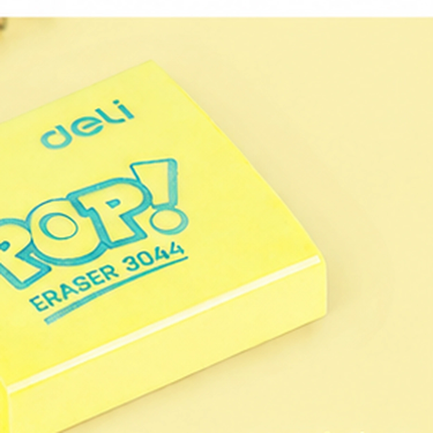 Close view of a butter yellow Deli Pop eraser with its POP! lettering and ERASER 3044 marking outlined in turquoise on the flat square face
