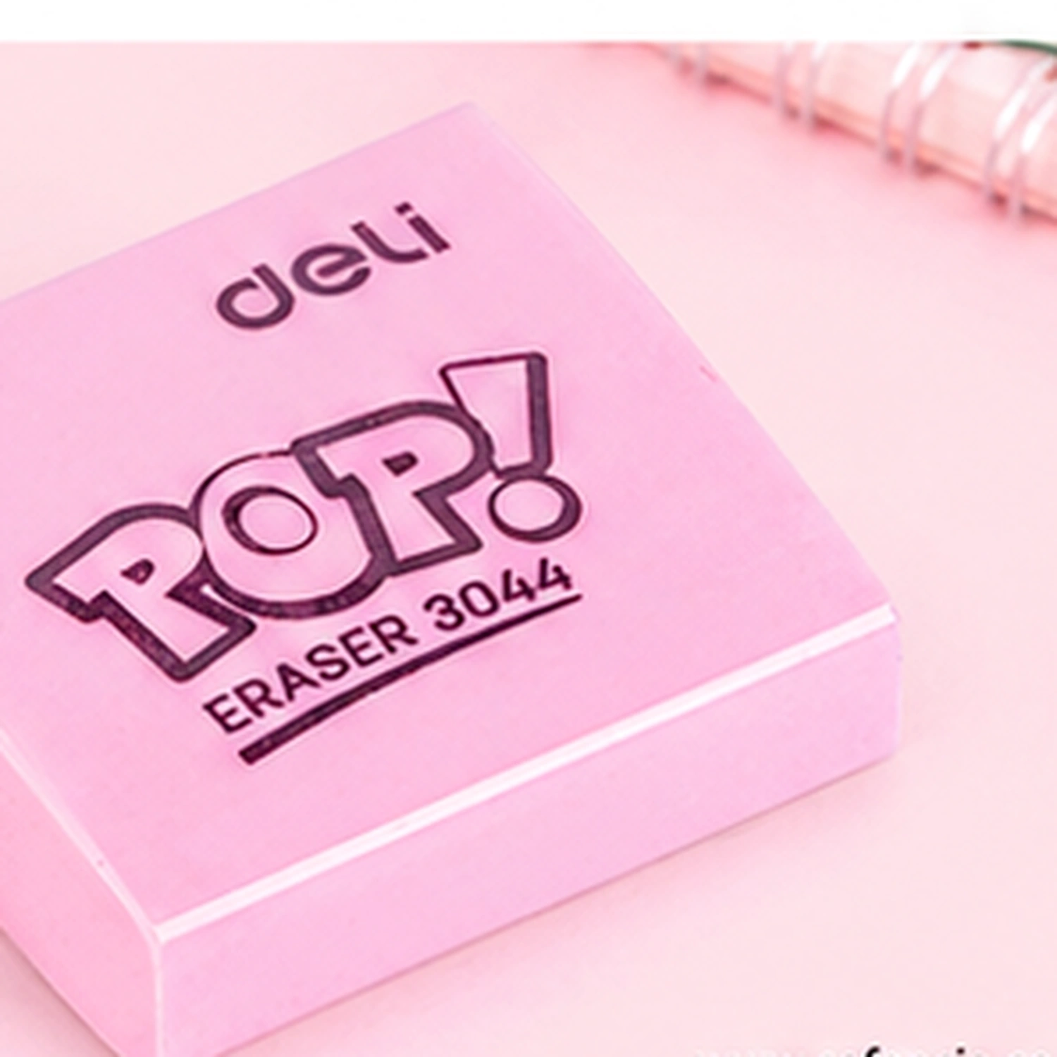 Close view of a pink Deli Pop eraser showing the deli name and the outlined POP! lettering with ERASER 3044 printed beneath it, a spiral notebook behind