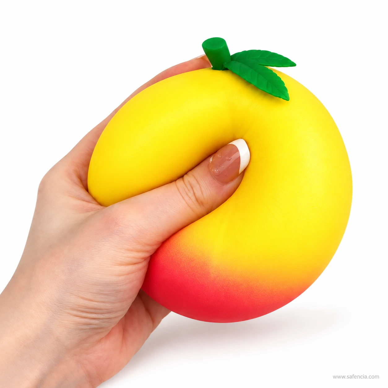 Hand holding the honey peach squishy with a thumb pressed deep into its soft side