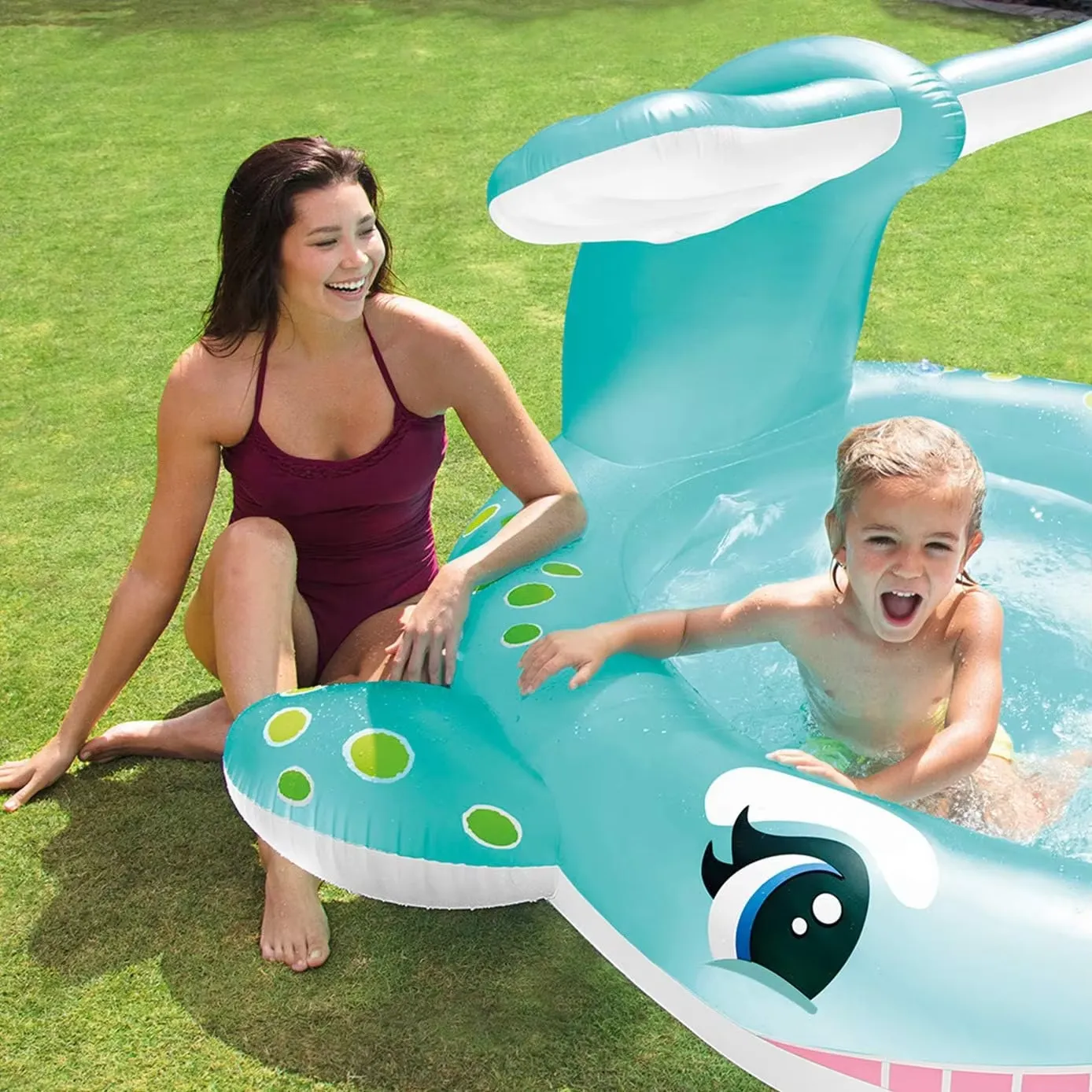Intex Whale Spray Pool on a lawn with a child playing inside and an adult beside the whale pool