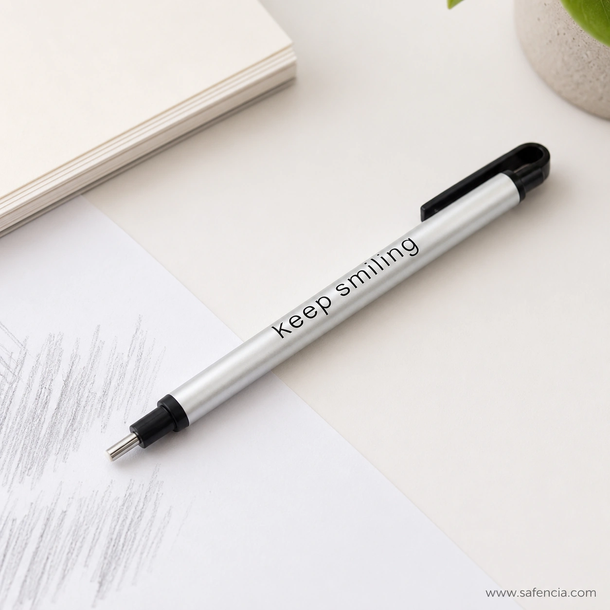 Keep Smiling eraser pen lying on a desk beside graphite pencil shading with the eraser core aimed at the sketch