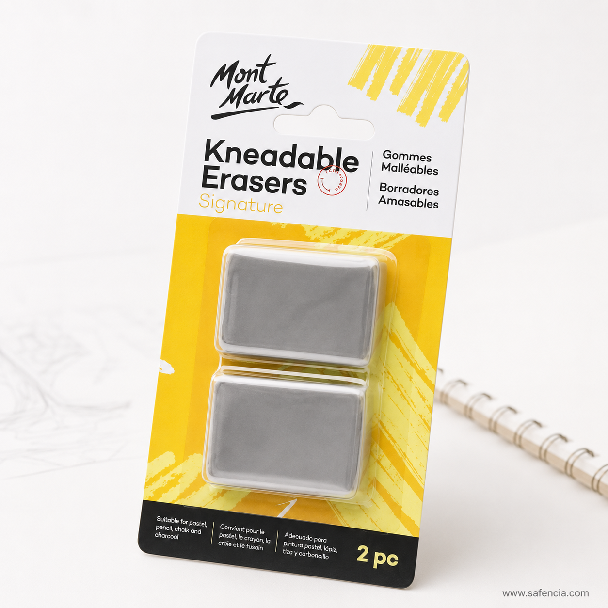 Mont Marte Kneadable Erasers Pack of 2 photographed at an angle beside a spiral-bound sketchpad and a pencil drawing
