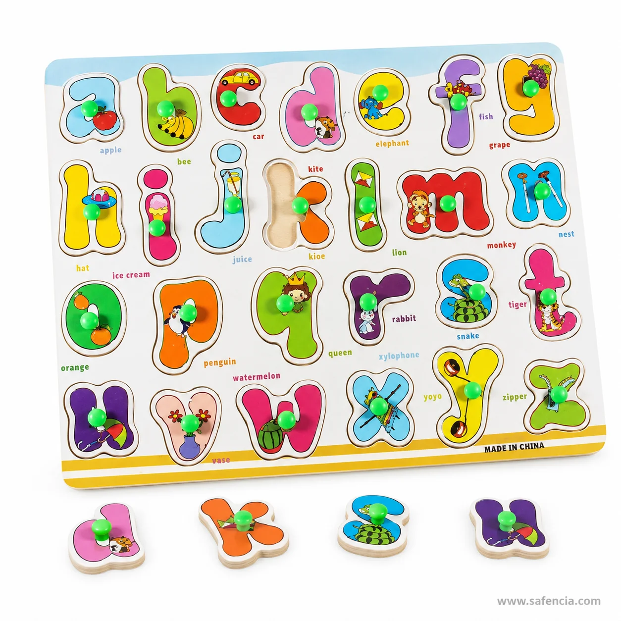 Four loose lowercase letter pieces with green knobs beside the wooden alphabet board
