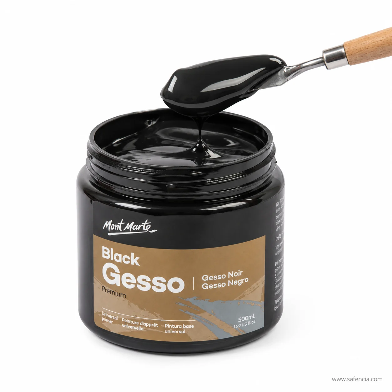 Black gesso jar with lid removed beside a brush and palette knife on a black-primed sheet
