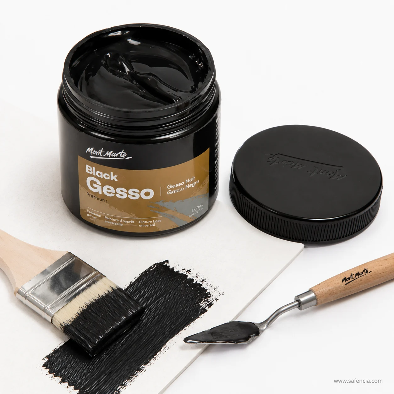 Palette knife lifting a thick ribbon of black gesso from the open jar