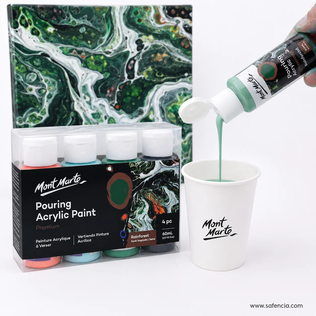 Mont Marte pouring acrylic bottle being squeezed into a paper cup beside a green poured canvas