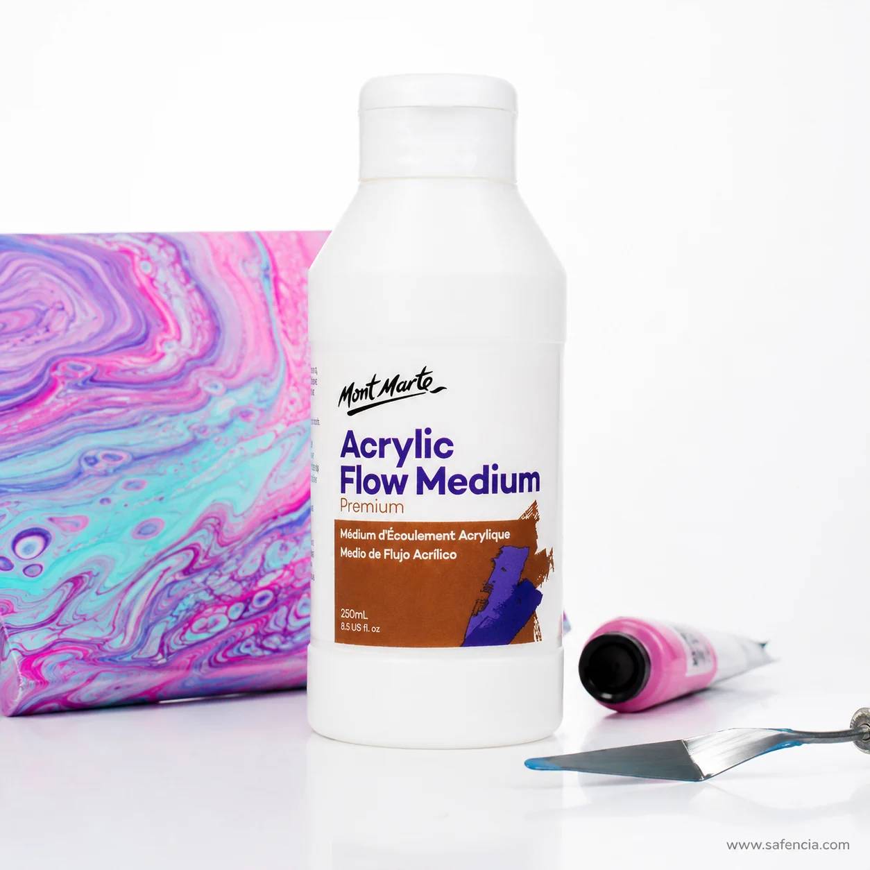 Flow medium bottle standing beside a pink and blue marbled acrylic panel and a palette knife