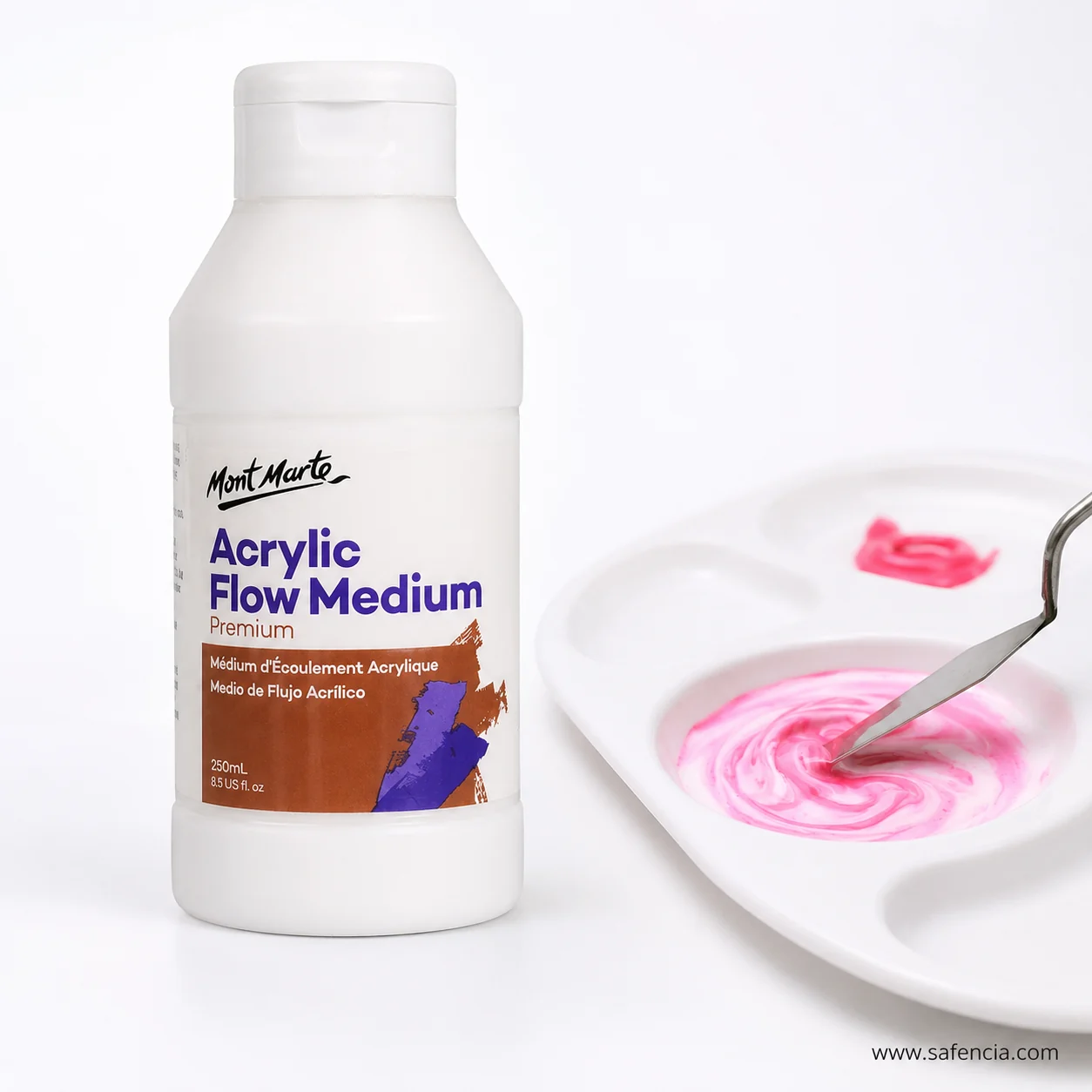 Flow medium bottle beside a white palette where pink acrylic is being stirred with a knife