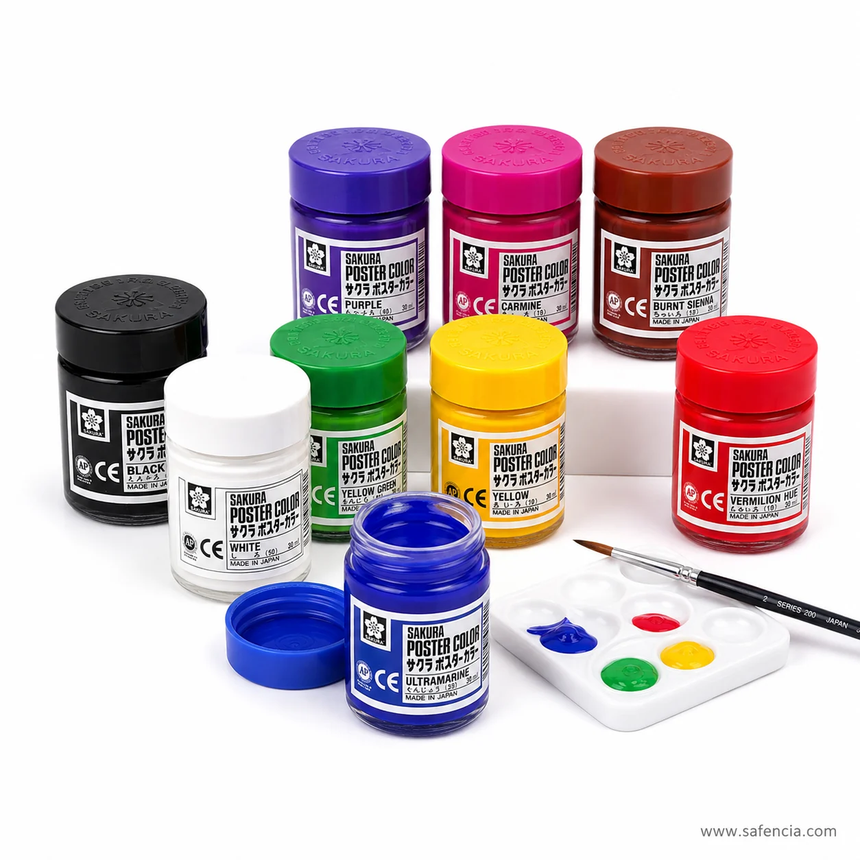 Sakura Poster Color jars beside a white mixing palette carrying wells of blue yellow red and green