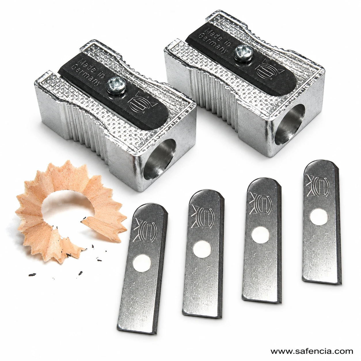 Silver aluminum handheld pencil sharpener with ridged sides beside curled pencil shaving