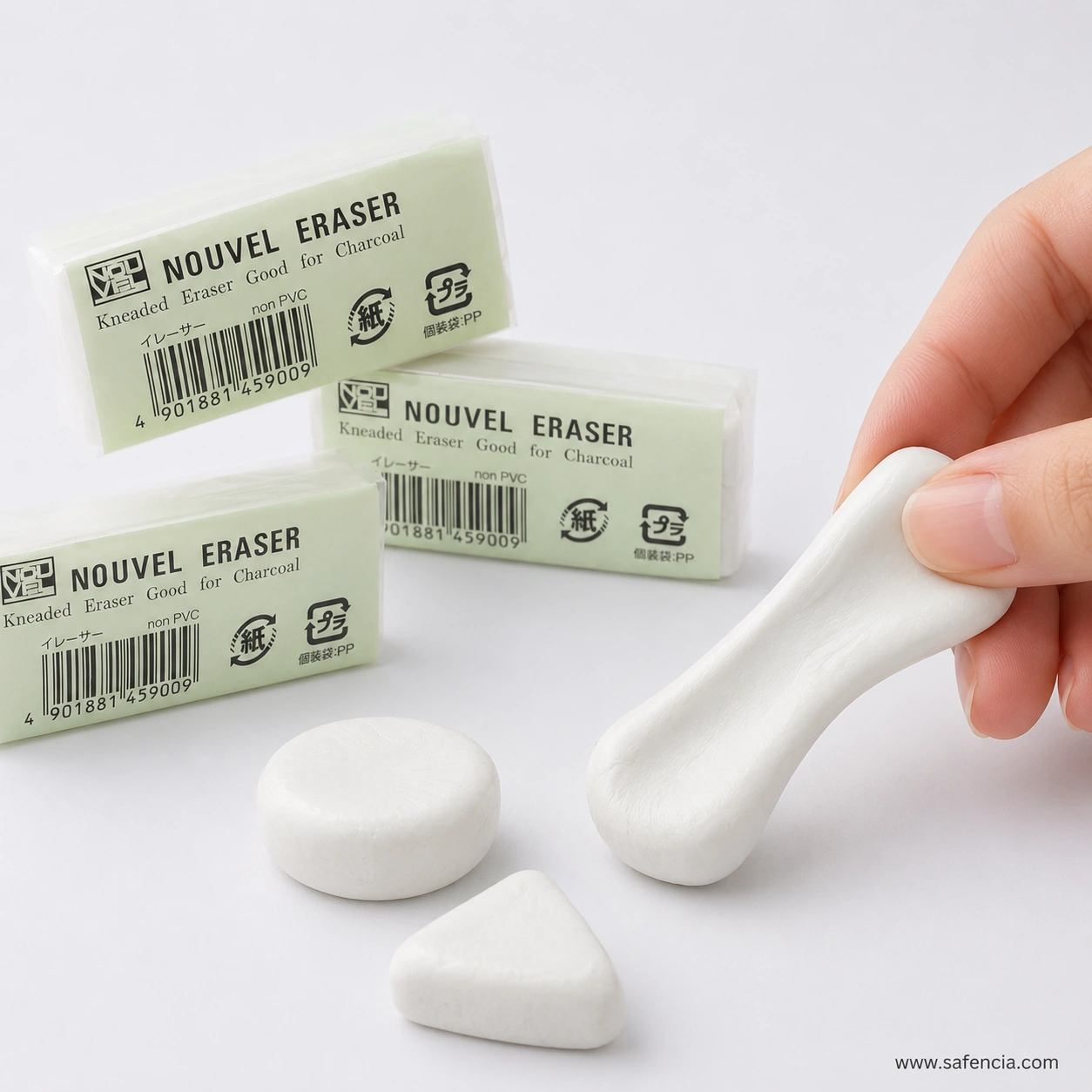 The white Sakura Nouvel kneaded eraser shaped three ways — a flat disc, a triangular wedge and a drawn-out point held between finger and thumb — beside three sealed packs